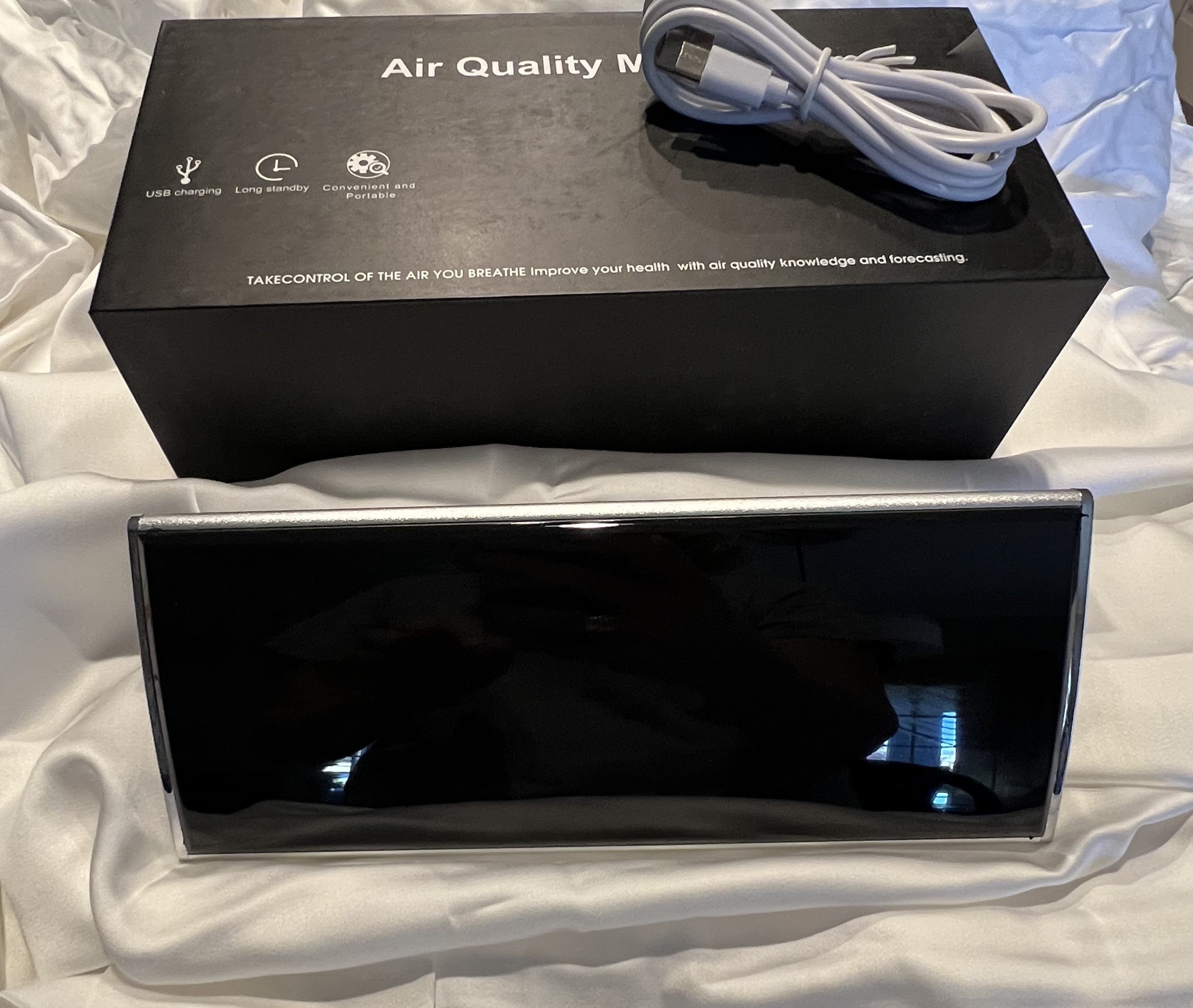 Air quality monitor with packaging and cable on a white surface