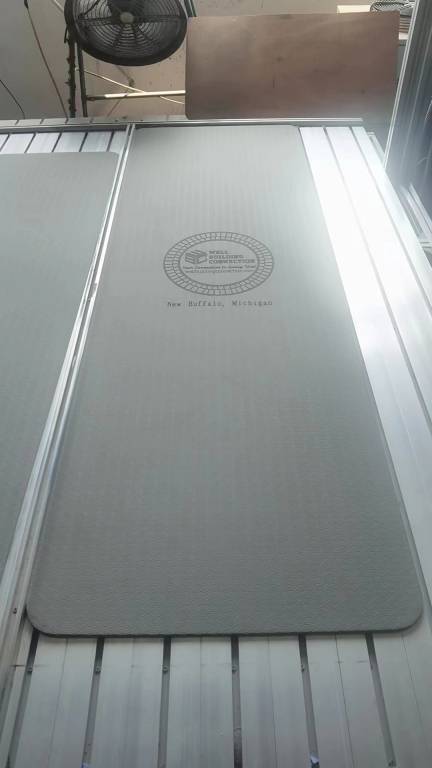 Gray yoga mat with a textured surface, displaying a logo and text indicating the Well Building Connection brand and location in New Buffalo, Michigan. Well Building Connection Exercise floor mat provides overall benefits for all fitness levels